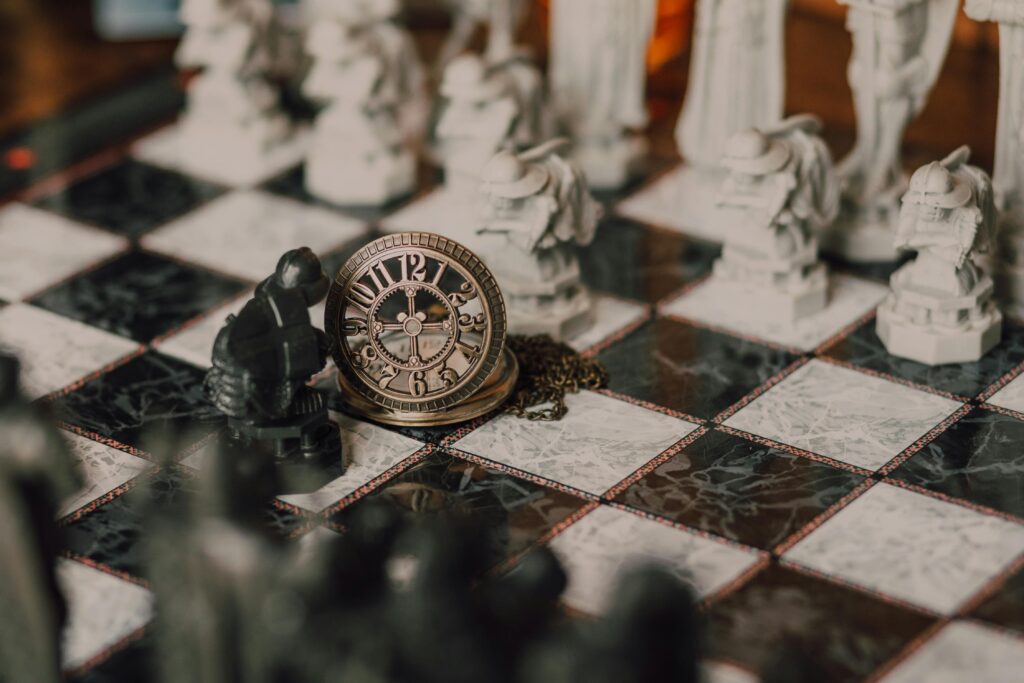 pexels-photo-7979098-7979098 Close-up of a detailed chess set inspired by fantasy themes with a magical vintage clock on the board.
